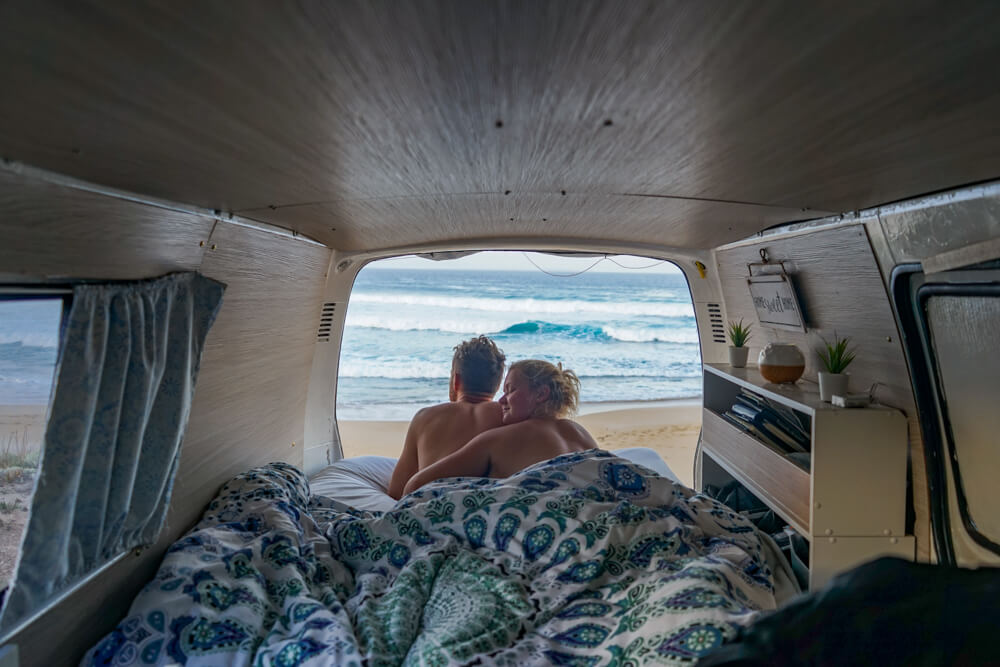 gemma and campbell lying in campervan overlooking the sea 