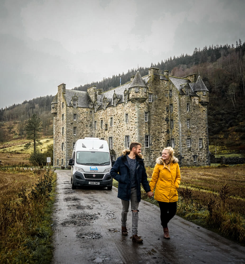 gemma and campbell in front of bunk campers campervan and castle