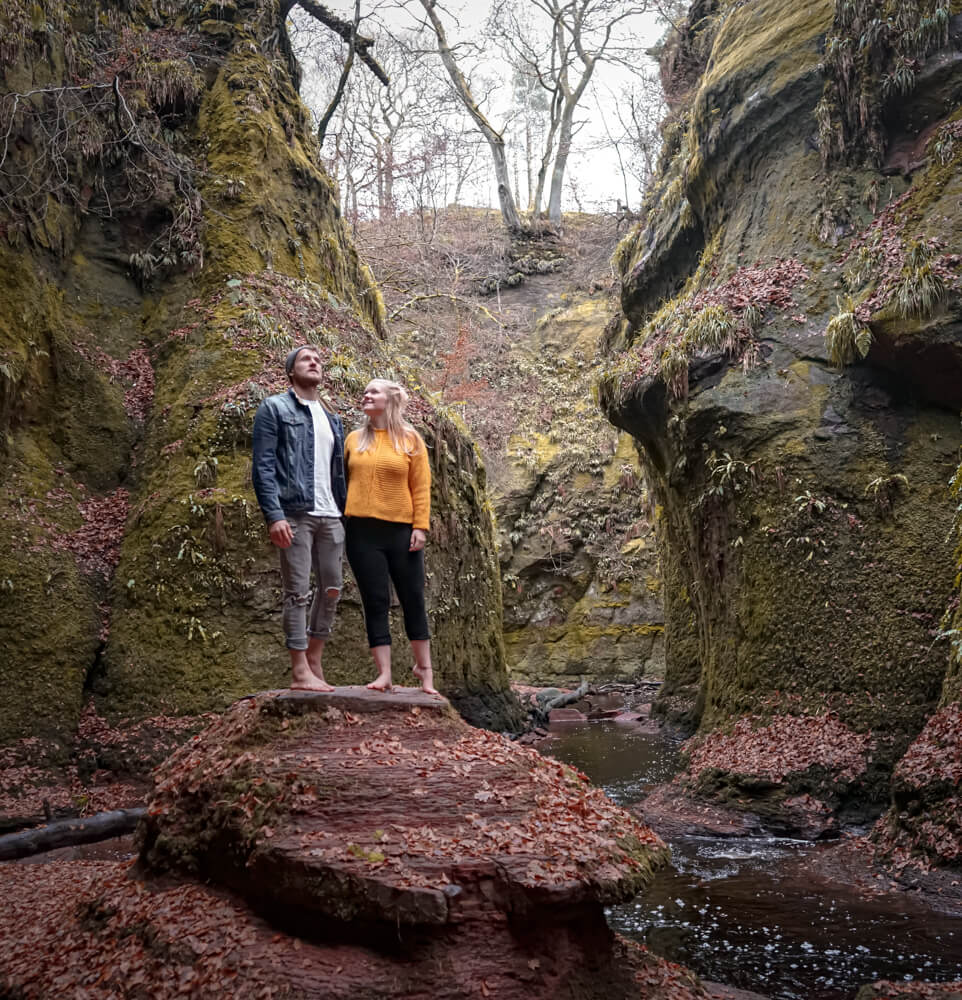 gemma and campbell standing in a red sandstone glen