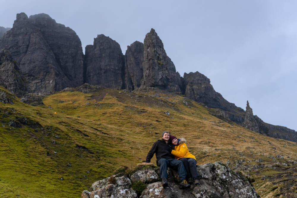 gemma and campbell sitting on a rock infront of the old man of storr