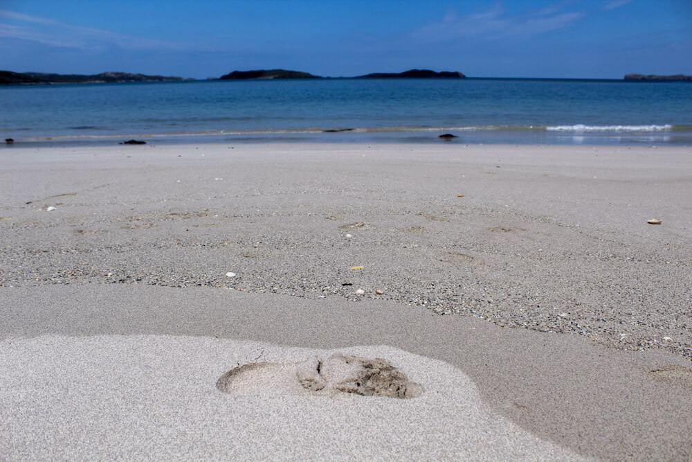 A footprint in the white sand at Coldbackie Beach.