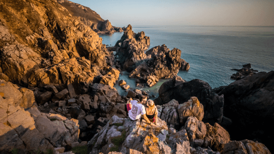 couple sitting on rocks overlooking sea