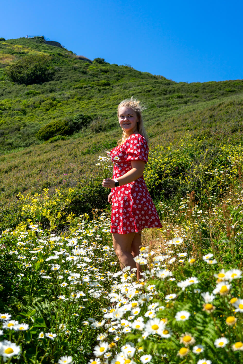 gemma standing in a flower field holding flowers 