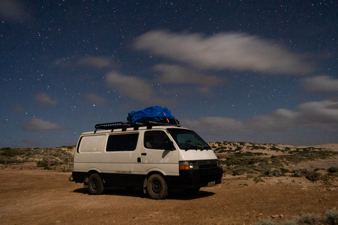 a campervan sits beneath a star filled sky