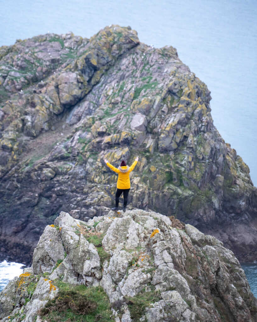 girl in yellow jacket standing on rocks