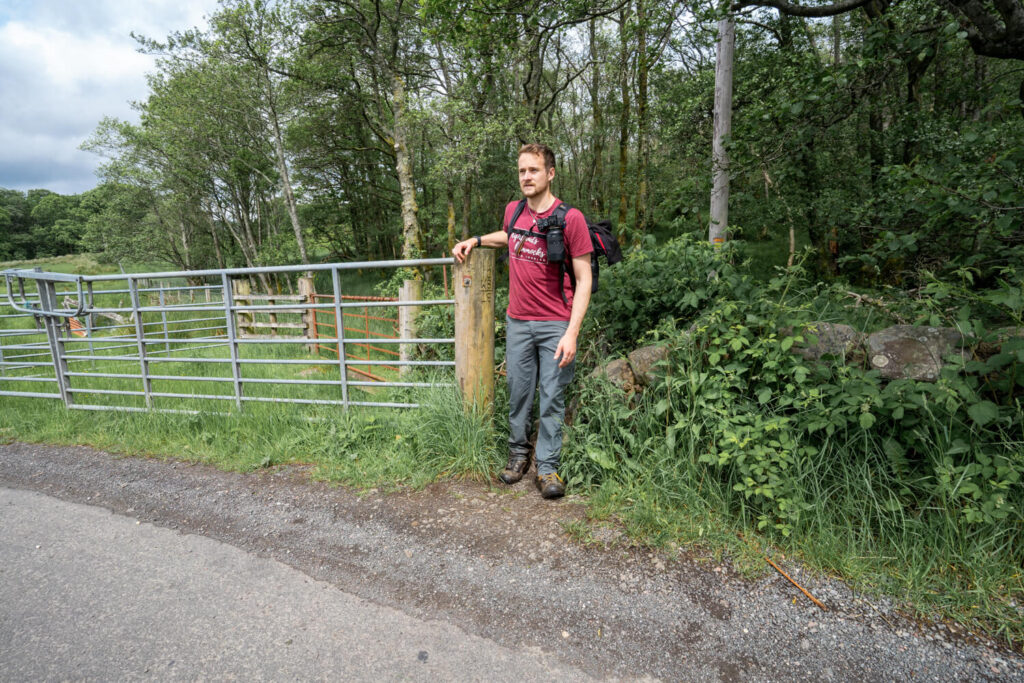 man standing beside gate on road