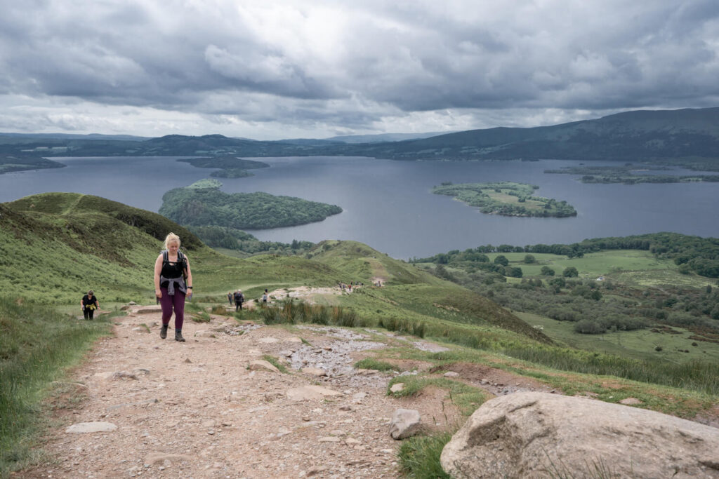 girl walking up will with loch view in background