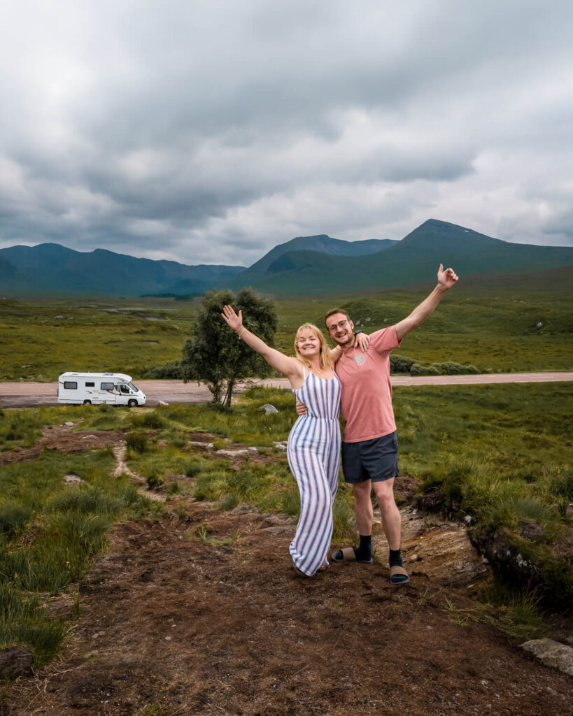 couple with arms in the air motorhome in background