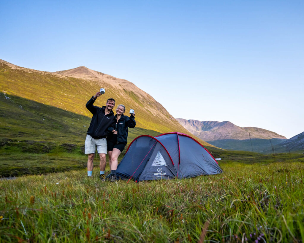 couple outside tent with mountain backdrop