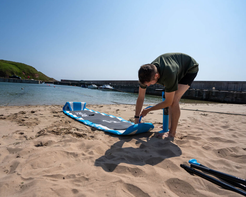 man pumping up paddle board at Cruden Bay