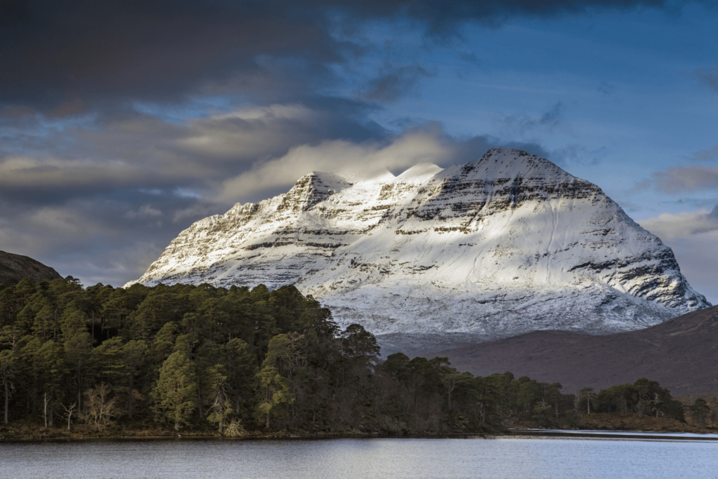 mountain covered in snow behind loch